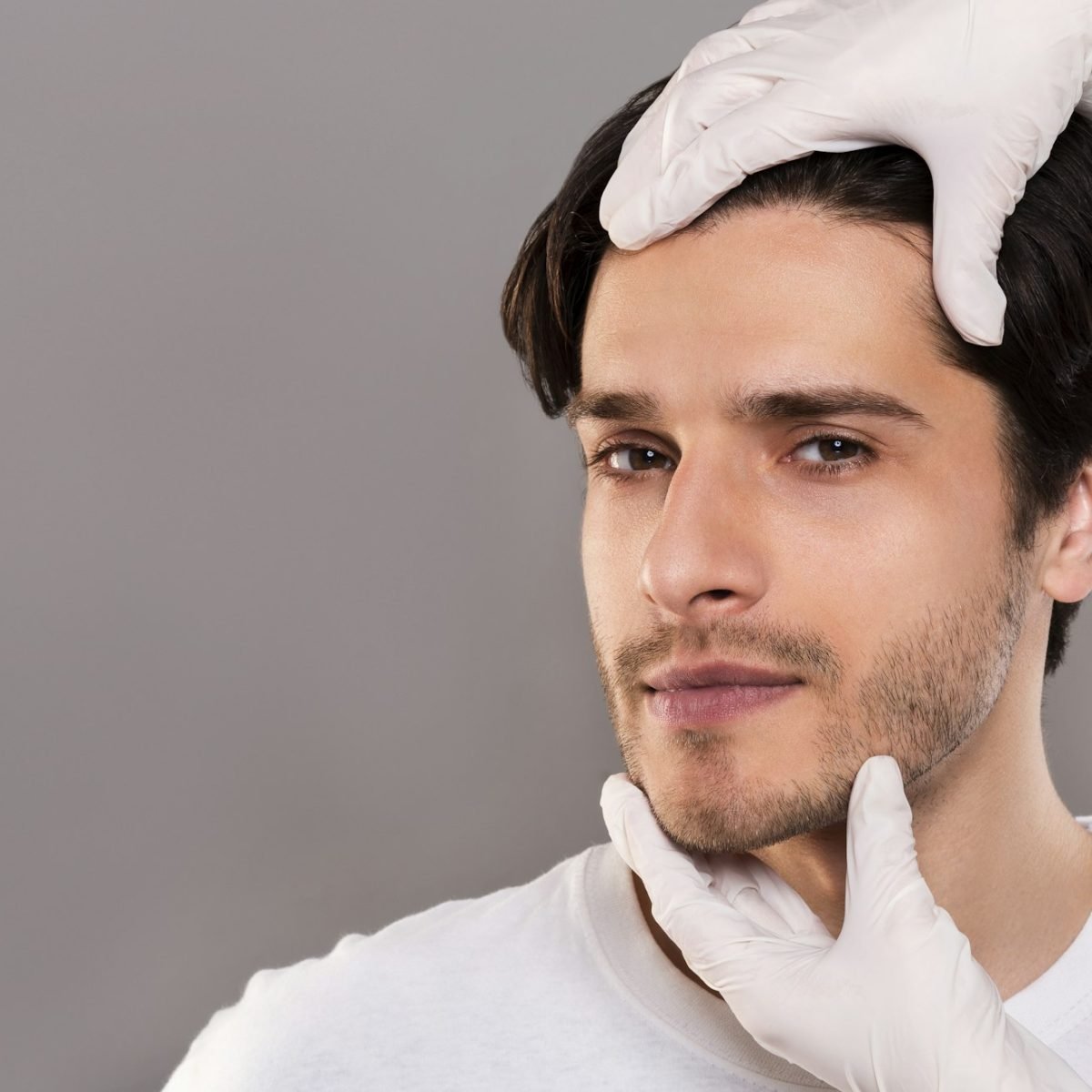 Plastic surgeon examining male patient face, empty space